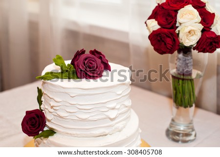 beautiful white cake and red bouquet on the table