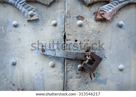 black metal padlock on green wooden old garage gates with handle.