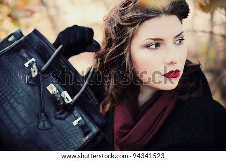 Fashion shot of a beautiful, professional model with a bag in her hands