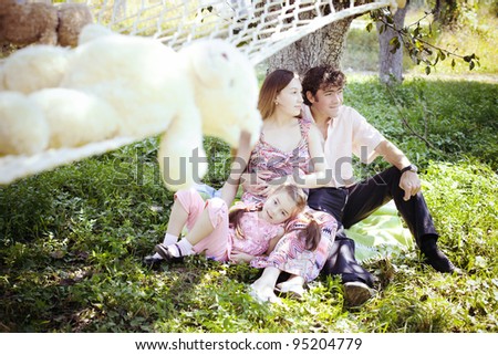 happy family sitting on the lawn in the garden next to the hammock