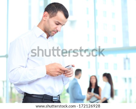 Handsome businessman using a smartphone. businessman standing inside modern office building looking on a mobile phone
