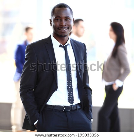 Portrait of smiling African American business man with executives working in background
