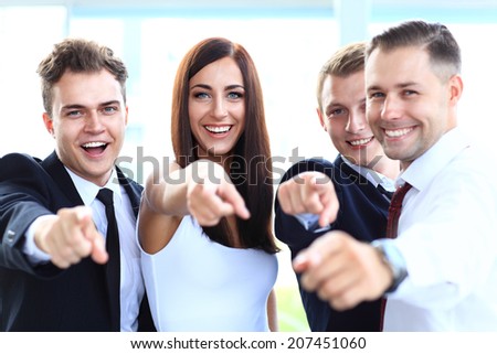 Happy diverse group of executives all pointing at you