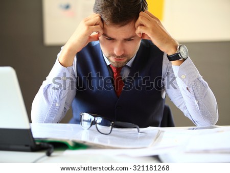 Stressed businessman with head in hands in his office