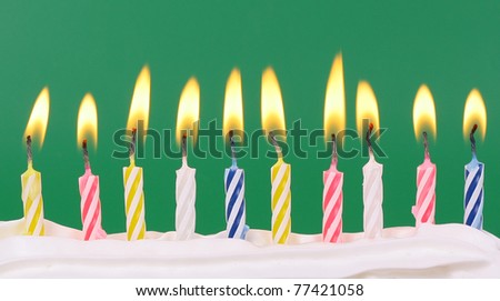 10 lit birthday candles in bright colors with red background