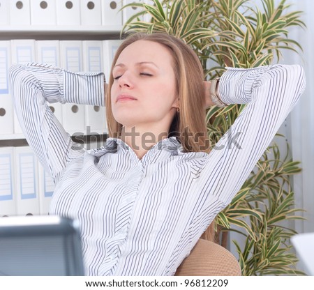 Portrait of cute business woman sitting in office and relaxing with hands behind head