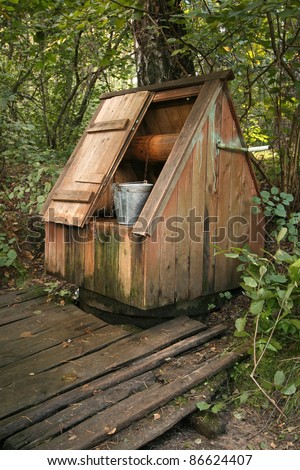 Well with an open door and a metal bucket in wood