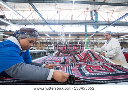CAPE TOWN, SOUTH AFRICA - AUG 2: A woman prepares material for cutting in a large clothing factory in Cape Town, South Africa on August 2, 2012