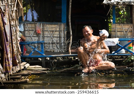 SIEM REAP, CAMBODIA - DECEMBER 09: A man baths in river water in a small floating village in Siem Reap, Cambodia on December 09, 2009
