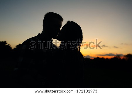 Happy couple kissing at sunset. Silhouette.