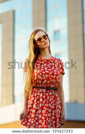 Beautiful girl in a red dress on a background of high-rise build