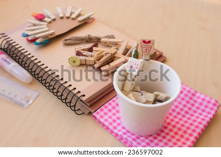 set of working out this morning, wooden clip set, notebook and etc. put on wooden table, concept of work that is done in a cheerful way makes a happy fun-filled day, focus to wooden clip in mini cup