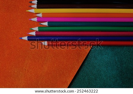multicolored pencils on orange and green abstract textured background