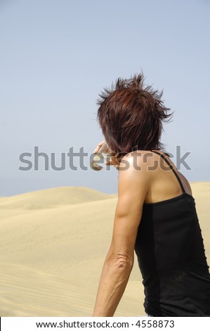Woman is drinking a fresh glass of cold water in desert.