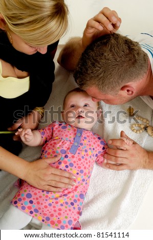 Mother and father are looking at their sweet smiling 4 month old baby.