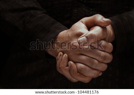 Hands clasped in Waiting, Black Background.