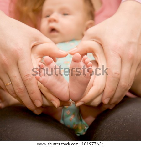 Baby feet in mother\'s and father\'s hands, heart-shaped. The symbol of protection, custody and parental love