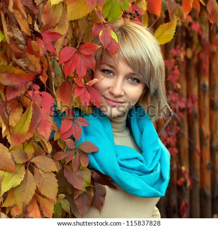 Autumn portrait a lovely young gray-eyed blond woman. A beautiful face is framed by bright colorful autumn leaves.
