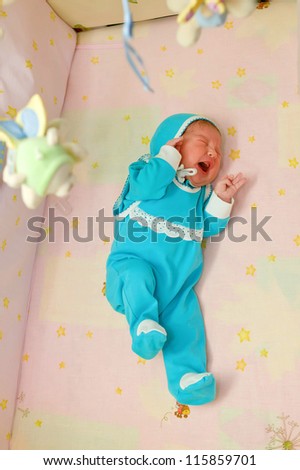 Crying newborn baby in the crib. He is lonely. Something bothers him.