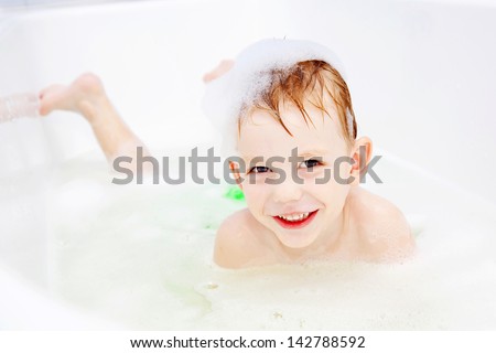 A little boy swimming in the bath and smiling