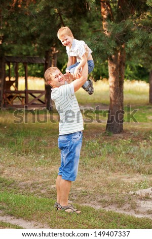 Happy father and son outdoors. Daddy raising up the child.