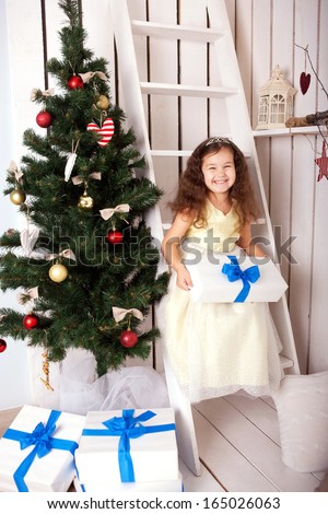 Happy smiling kid holding gifts near the Christmas tree. Christmas, New Year, holiday concept, ready for your text, letters, logo or symbols.