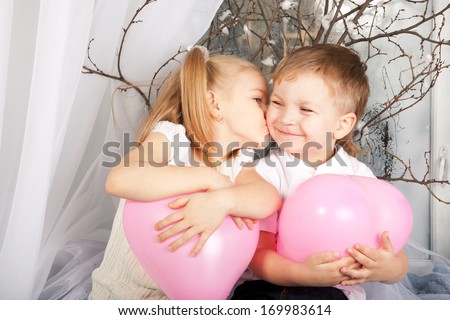Little couple of kids hugging, kissing and holding heart balloons. Valentine\'s Day and love concept.