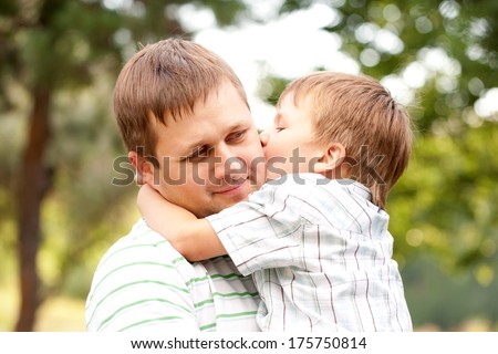 Happy father and son outdoors. Child kissing daddy.