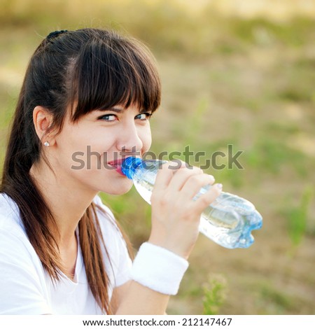 Runner woman drinking water after jogging outdoors. Healthy lifestyle, jogging and fitness concept.