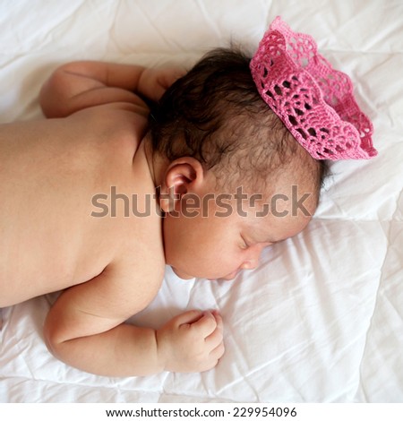 Black small newborn baby princess sleeping on a bed in a crown. Dreams and innocence concept.
