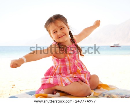 Smiling kid is having fun on the lounger on the beach. Summer holidays.