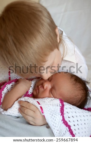 Multiracial happy family. White brother hugging black newborn sister.