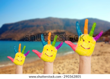 Smiley on family hands against beach and blue sea background. Summer vacation and family freedom concept with copy space