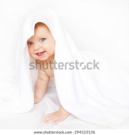 Baby playing hide and seek under the towel and showing tongue.