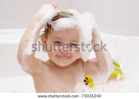 Cute baby is washing her hair in bath. The symbol of purity and hygiene education