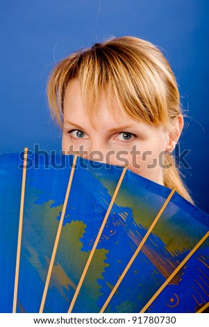 Young beautiful blond woman with a Japanese umbrella. Isolated on blue.