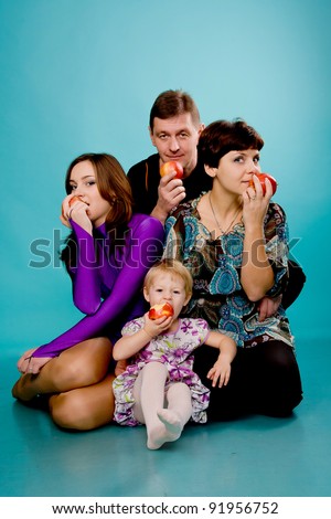 Father, mother and two daughters eating apples. Isolated on turquoise