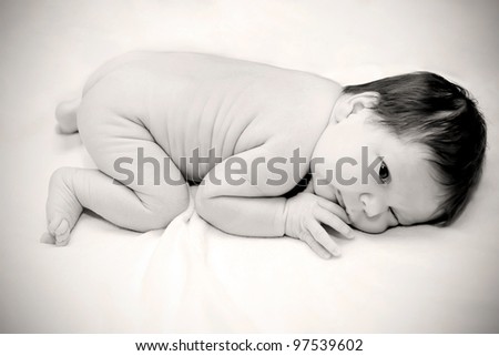Newborn sleeping child on white blanket. Black and white