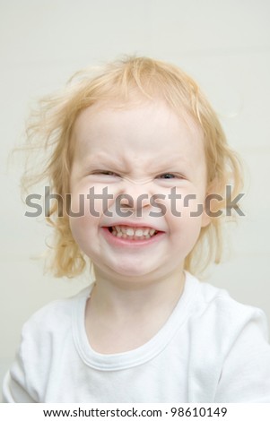 The shaggy little blond girl with blue eyes smiling joyfully with blank white shirt. Ready for your design or logo