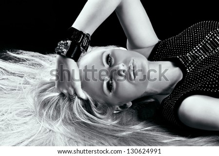 Black and white portrait of a laying beautiful blonde woman with hair spread on the floor
