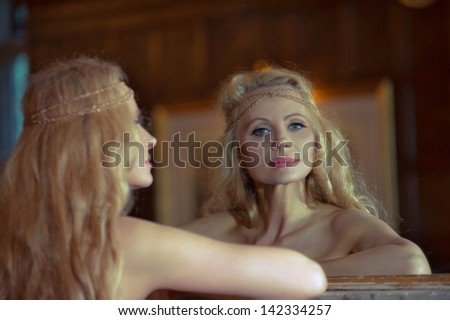 Beautiful blonde woman looking at herself in the mirror