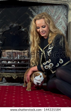 Blonde woman with an english bulldog puppy dog in luxury room