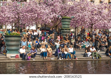 STOCKHOLM, SWEDEN - May 9: People relaxing in the sun by a pond and blossoming cherry trees in park  on May 9, 2013 in Stockholm.