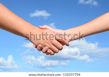 Hand shake between a man and a woman on blue sky background