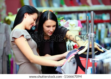 two happy women shopping in clothes store