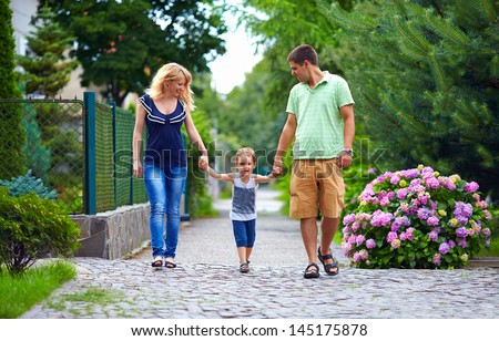 happy family of three persons walking the street