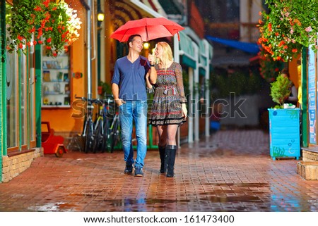 happy couple walking under the rain on cozy colorful street