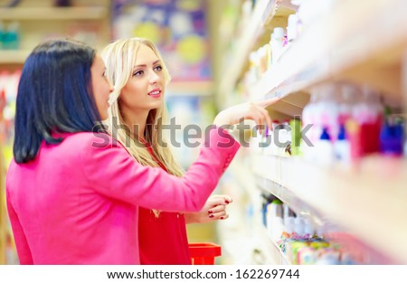 beautiful women choose personal care product in supermarket