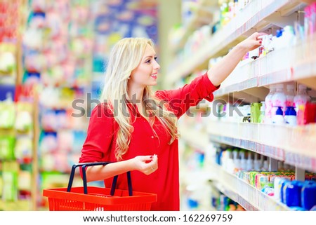 beautiful woman choosing personal care product in supermarket