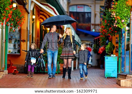 happy family walking under the rain on cozy colorful street